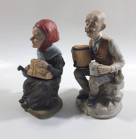 Old Man Sitting With Keg Barrel and Beer Stein and Old Woman Sitting with Umbrella and Packages Porcelain Figurines Set of 2