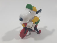 Vintage United Feature Peanuts Snoopy Learning To Ride A Bike On Bicycle With Training Wheels 2 1/2" Tall PVC Toy Figure Made in Hong Kong