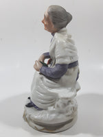 Old Woman Sitting with Basket of Bread Holding a Pear and Banana 6 1/2" Tall Porcelain Figurine
