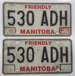 Set of 2 1985 Friendly Manitoba White With Black and Red Letters Metal Vehicle License Plate Tag 530 ADH