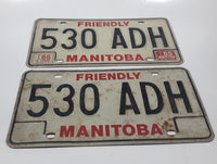 Set of 2 1985 Friendly Manitoba White With Black and Red Letters Metal Vehicle License Plate Tag 530 ADH
